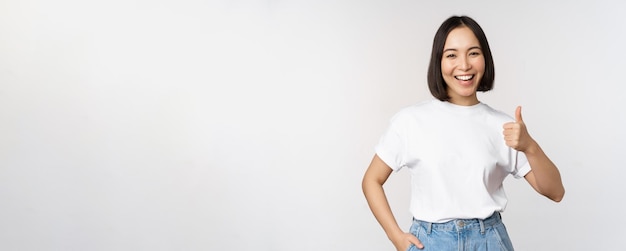 브랜드나 com을 추천하는 승인에 엄지손가락을 치켜세워 웃고 있는 행복한 아름다운 한국 여성