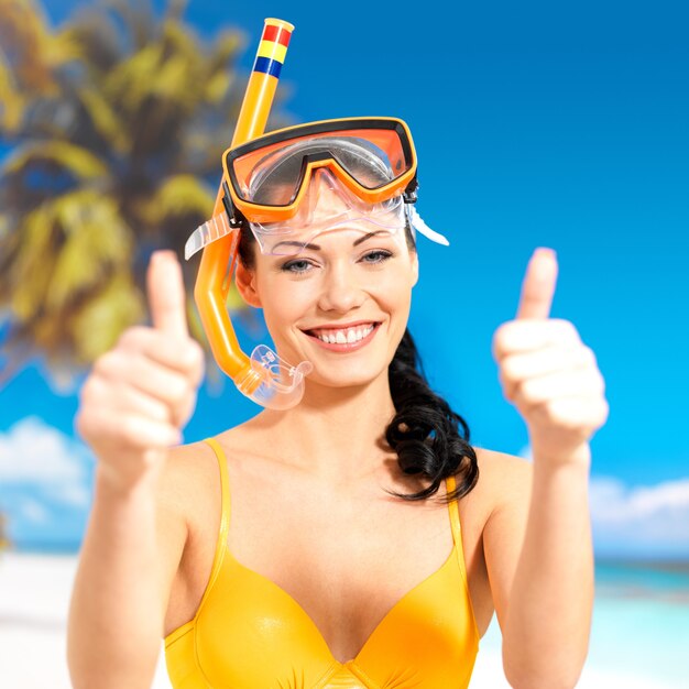 Счастливая красивая женщина на пляже с большими пальцами руки вверх знаком.