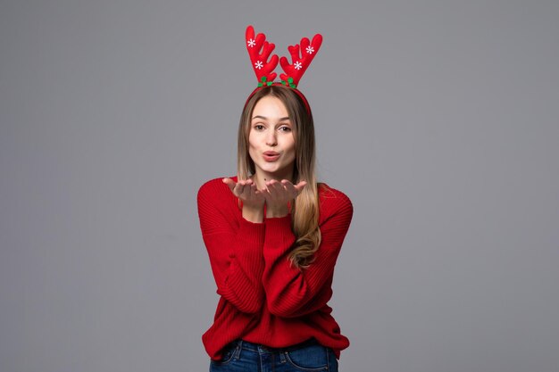 Happy beautiful woman with reindeer horns on her head with peace gesture on gray wall