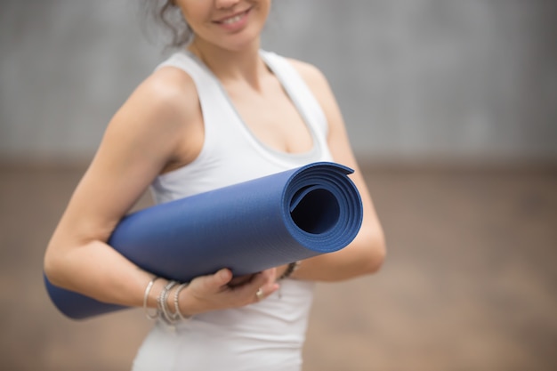 Happy Beautiful Yogi woman holding her mat, close up