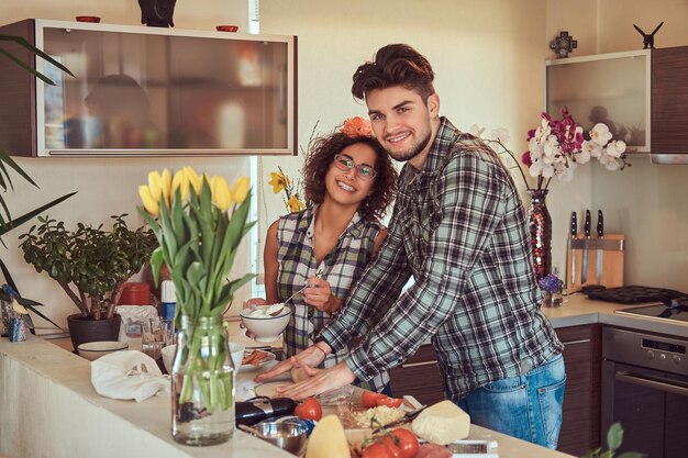 Happy beautiful young couple cooking in the kitchen at home.
