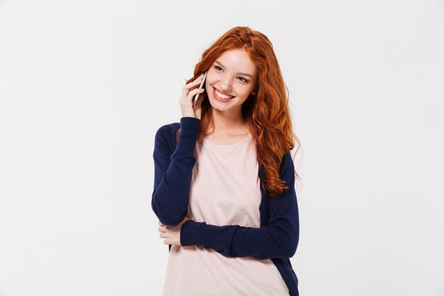 Happy beautiful young redhead lady talking by mobile phone.