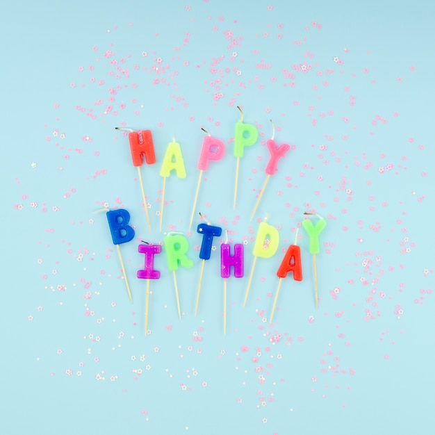 Free photo happy birthday candles and glitter on blue background