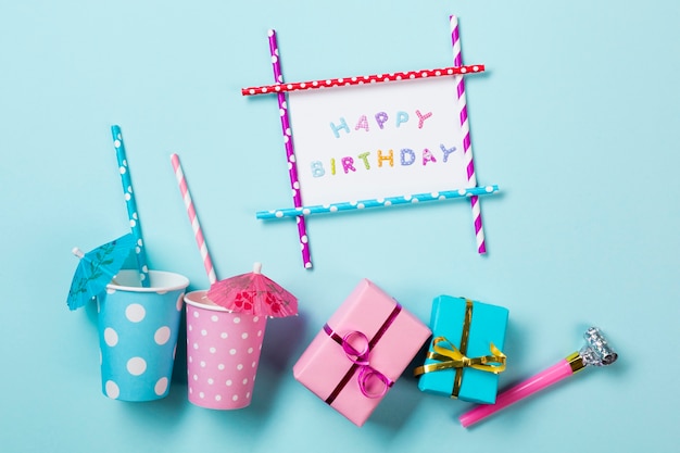 Поздравительная открытка с днем рождения рядом с тонущими очками подарочные коробки и трубач на синем фоне