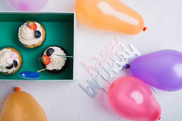 Happy birthday inscription with cupcakes on table