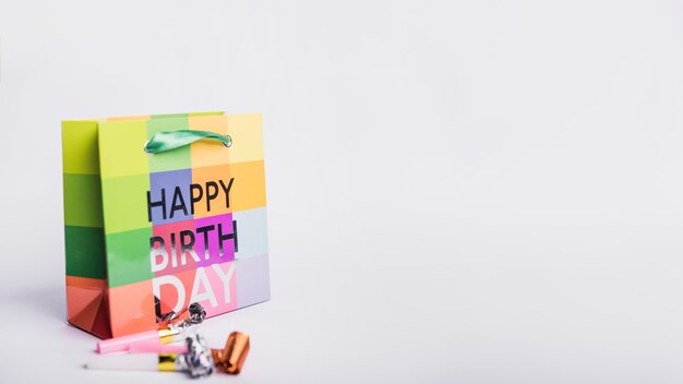 Happy birthday shopping bag and party blowers on white background