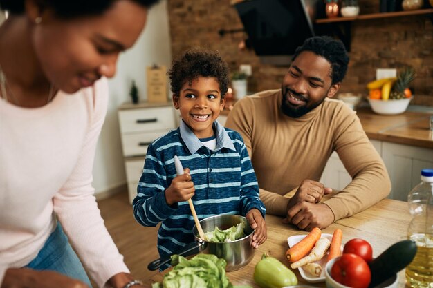 부엌에서 부모와 함께 건강한 음식을 준비하는 행복한 흑인 소년