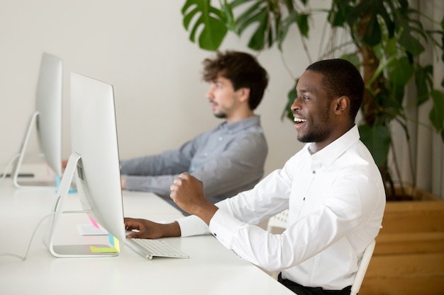 Happy black employee excited by online win or good result