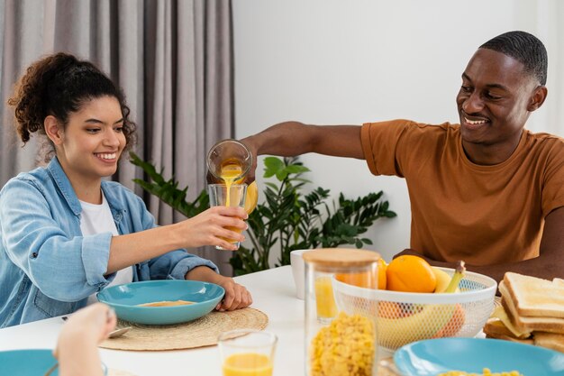 幸せな黒人家族のカップルがジュースを飲む