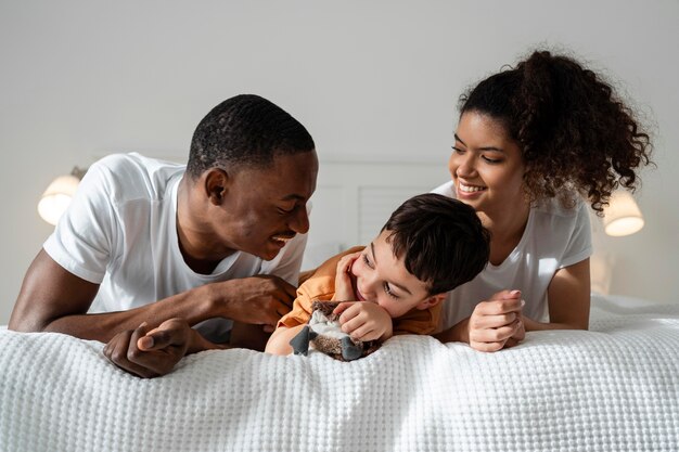 ベッドに横たわっている間素晴らしい時間を過ごしている幸せな黒人家族