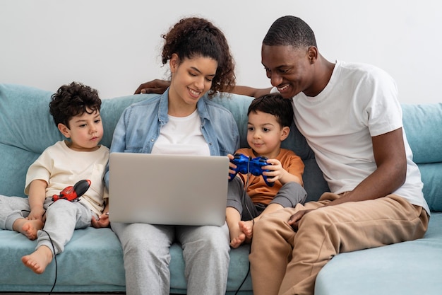 Счастливая черная семья смотрит что-то на ноутбуке и смеется