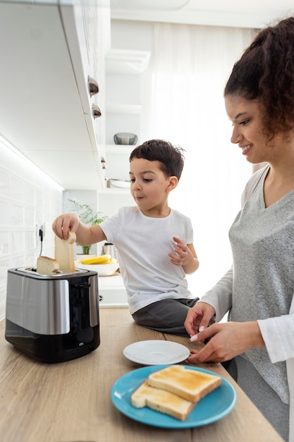 Foto gratuita bambino nero felice che aiuta sua madre con la colazione