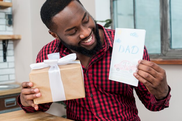 Счастливый черный человек, держащий открытку и подарок