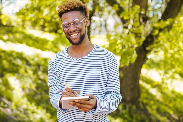 Happy black man posing with notepad