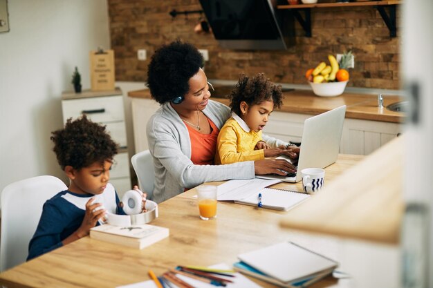 Happy black mother working on a computer while daughter is sitting on her lap at home