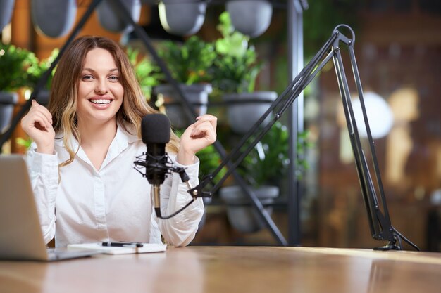 happy blogger woman giving interview into microphone