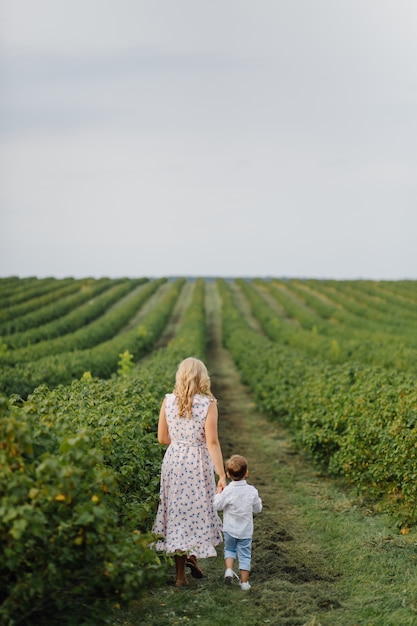 Happy blond woman and cute little boy standing in summer garden