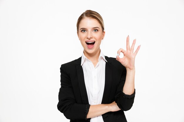 Happy blonde business woman showing ok sign and with open mouth over white