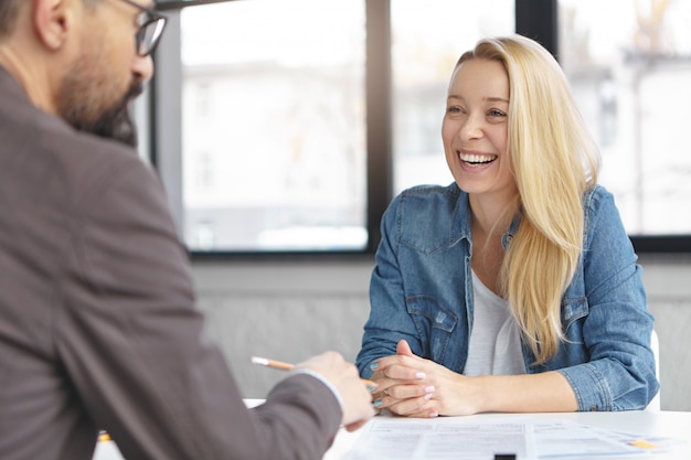 Happy blonde female manager has conversation with male colleague
