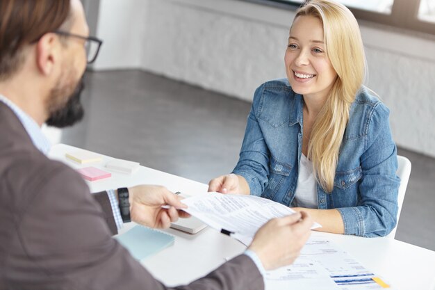 Happy blonde female manager has conversation with male colleague