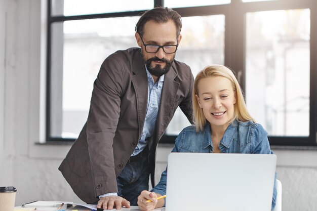 Happy blonde female manager has conversation with male colleague