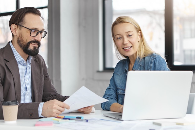 Happy blonde female manager has conversation with male colleague