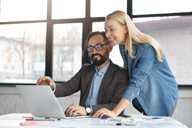 Happy blonde female manager has conversation with male colleague