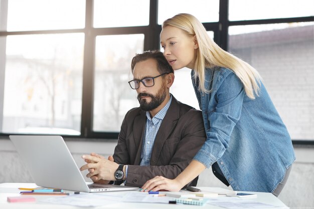 Happy blonde female manager has conversation with male colleague