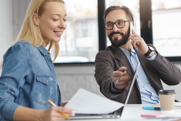 Happy blonde female manager has conversation with male colleague