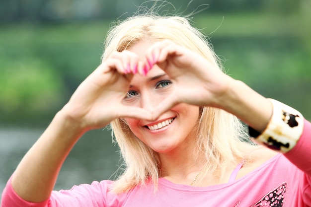 Foto gratuita cuore di formazione biondo felice con le sue mani