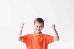 Бесплатное фото Счастливый мальчик сжимая кулак, делая да жест на белой стене