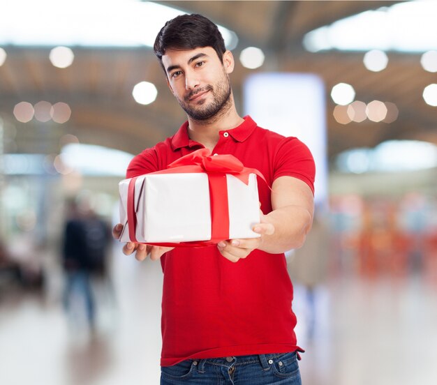 Felice ragazzo in possesso di un regalo con un fiocco rosso