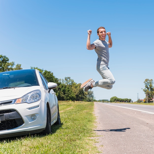 Happy boy jumping on the road next to car