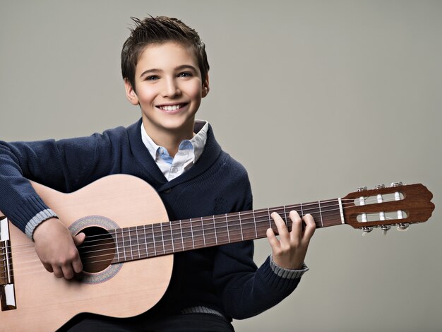 アコースティックギターで遊んでいる幸せな少年。