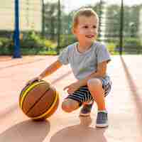 Foto gratuita ragazzo felice che gioca a basket all'aperto