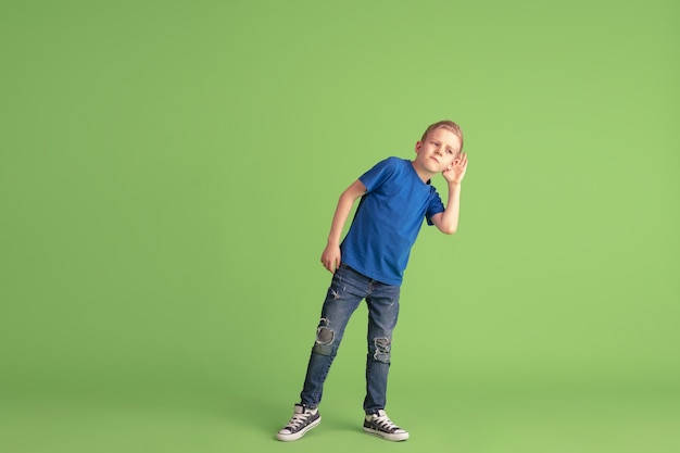 Счастливый мальчик играет и веселится на зеленой стене студии