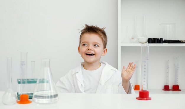 Scienziato ragazzo felice in laboratorio con provette