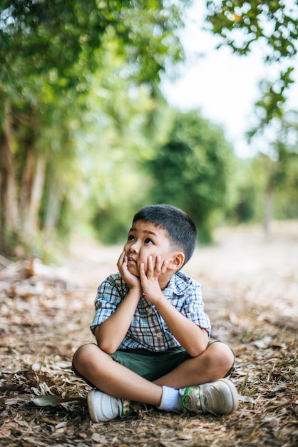 Happy boy sitting and thinking alone in the park