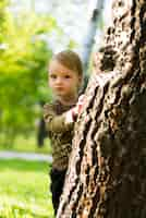 Free photo happy boy behind a tree