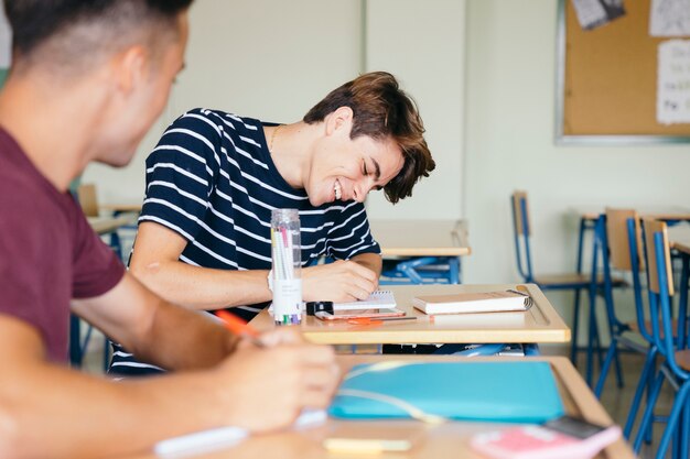 Happy boy writing in class