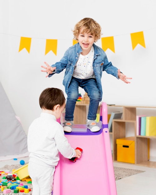 Бесплатное фото Счастливые мальчики играют с игрушками рядом с горкой