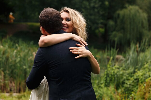 Happy bride hugs her groom tender standing in the park