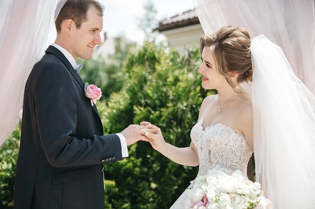 행복한 신부는 그녀의 남편을 위해 결혼 반지를 착용