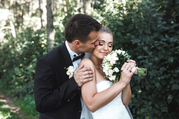 Happy bride with her wedding bouquet and her husband