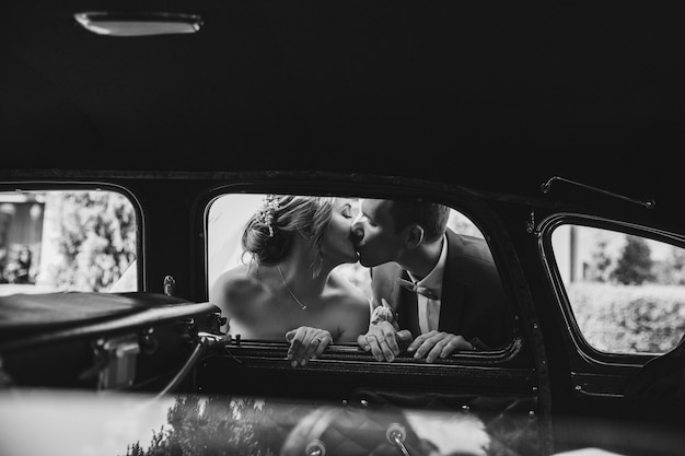 幸せな花嫁は車の中でキスしています