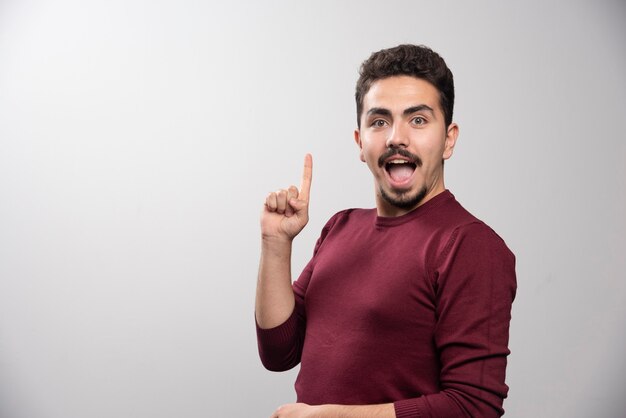 A happy brunette man showing a finger up and posing .