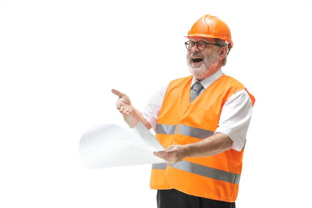 Счастливый строитель в строительном жилете и оранжевом шлеме, улыбаясь в студии