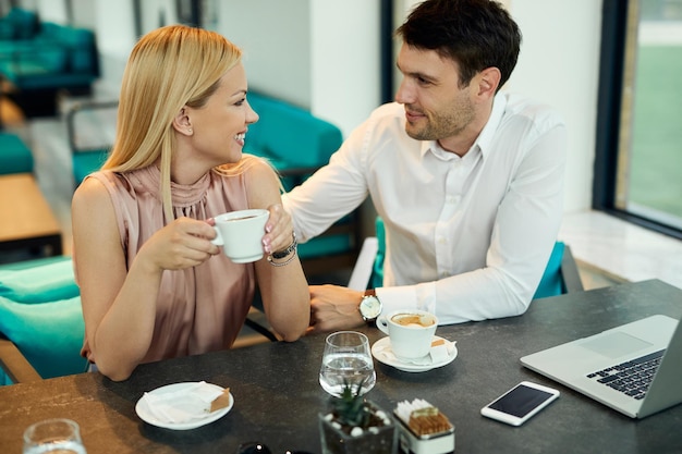 Happy business colleagues communicating while enjoying on coffee break in a cafe