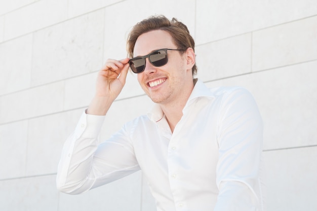 Счастливый деловой человек, регулируя солнцезащитные очки на открытом воздухе