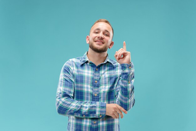 The happy business man standing and smiling against blue wall